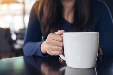 Holding ve vintage kafede sıcak kahve içme bir kadın portre resim