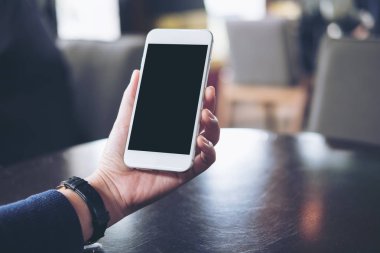 Mockup görüntüsünü tutan ve modern ofis boş siyah perde ile beyaz cep telefonu arayan bir kadın eli