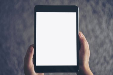 Mockup görüntü oturan ve siyah tablet pc gri halı ile boş beyaz ekran ile arka planda tutan bir kadın