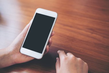 Antika ahşap masanın üzerine boş siyah perde ile beyaz cep telefonu tutan el mockup görüntü 