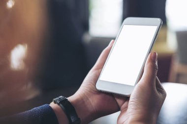 Cafe ahşap masa üzerinde beyaz cep telefonu boş beyaz ekran ile holding eller mockup görüntü