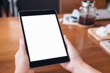 Kafede ahşap masa arka plan üzerinde siyah tablet pc ile beyaz boş perde holding eller mockup görüntü