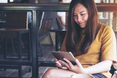 Seyir ve modern kafede tablet kullanarak gülen yüz ile güzel bir Asyalı kadın