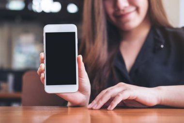 Güzel bir kadın tutarak ve restoranda boş siyah perde ile beyaz cep telefonu gösterilen mockup görüntü 