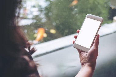 Bir kadın tutarak ve gölet ve doğa arka plan ile boş ekran ile beyaz akıllı telefon kullanarak mockup görüntü