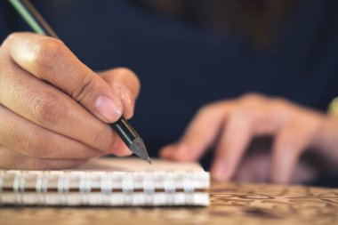Kadın eli defter ile ahşap masa arka plan üzerinde yazma görüntüsünü kapatmak
