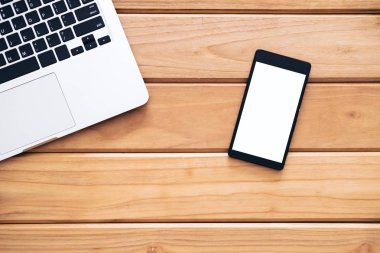 Mockup görüntü boş beyaz ekran ve gümüş renk laptop vintage ahşap masa arka plan üzerinde siyah cep telefonu