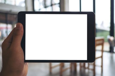 Holding ve kafede siyah tablet pc boş beyaz ekran ile gösterilen bir adamın elini mockup görüntü