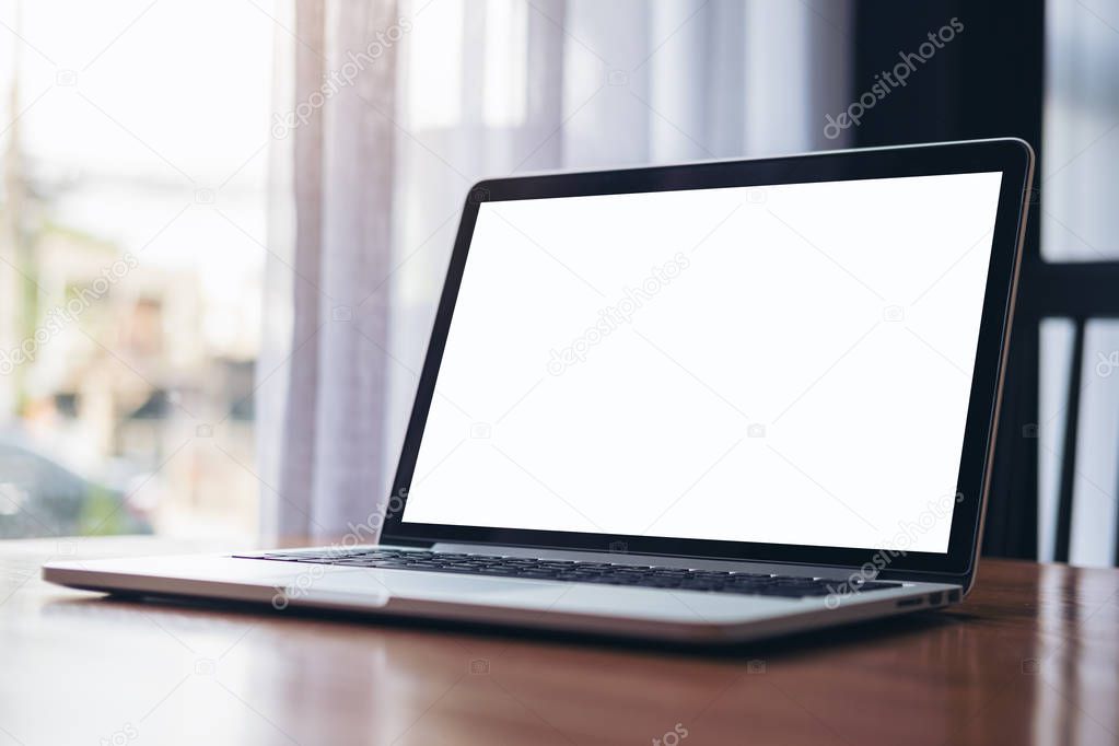 Mockup image of laptop with blank white screen on wooden table near by window in modern cafe