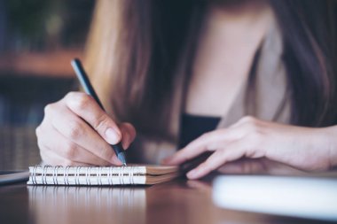 Ahşap masa arka planda office ile defter üzerinde yazılı bir iş kadını closeup görüntü 