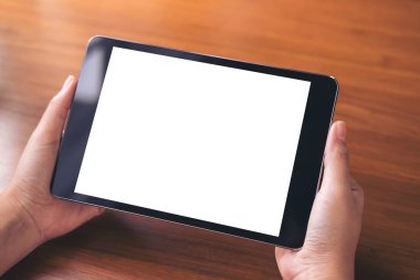 Antika ahşap masa arka plan üzerinde siyah tablet pc boş beyaz ekran ile holding eller mockup görüntü