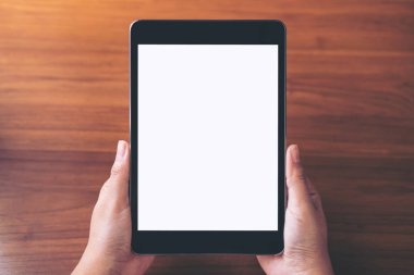 Antika ahşap masa arka plan üzerinde siyah tablet pc boş beyaz ekran ile holding eller mockup görüntü