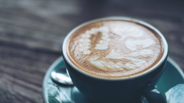 Bir fincan sıcak latte kahve latte sanat vintage ahşap masa üzerinde mavi kahve Kupası ile