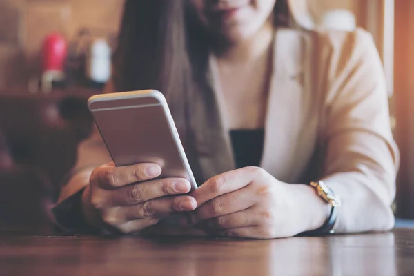 Bir güzel Asya iş kadını ile kullanarak ve modern café'akıllı telefon bakarak gülen yüz
