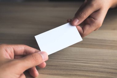 İşadamı, ahşap masa geçmişi olan iş kadınına boş bir kartvizit veriyor.