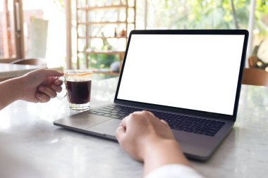 Modern kafede kahve içerken boş beyaz masaüstü ekran kullanan ve yazan ellerin görüntüsü