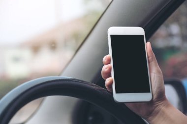 Bir el ele tutuşmanın ve yolda araba sürerken boş siyah masaüstü ekran ile beyaz cep telefonu kullanmanın görüntüsü