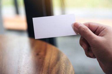 Ellerinde boş bir kartvizit var. 