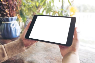 Kafe 'de elinde boş beyaz masaüstü ekranı olan siyah tablet bir kadının görüntüsü 
