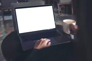 Kafede kahve içerken laptopta beyaz ekran kullanan ve daktilo yazan bir iş kadını görüntüsü.