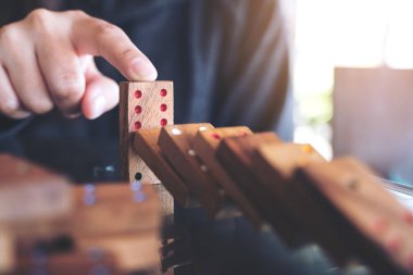 Tahta domino oyununun masaya düşmesini engellemeye çalışan bir elin yakın plan görüntüsü.