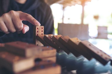 Tahta domino oyununun masaya düşmesini engellemeye çalışan bir elin yakın plan görüntüsü.