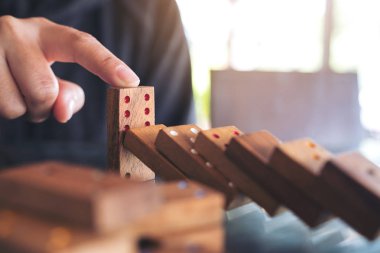 Tahta domino oyununun masaya düşmesini engellemeye çalışan bir elin yakın plan görüntüsü.