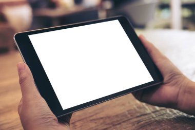 Cafe ahşap masa arka plan üzerinde siyah tablet pc ile beyaz boş perde holding eller mockup görüntü