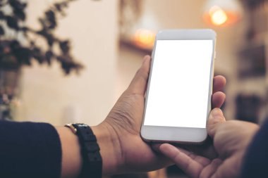 Mockup görüntü tutarak ve vintage kafede boş ekran ile beyaz cep telefonu kullanarak kadının el