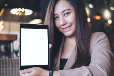 Holding ve modern kafede siyah tablet pc boş beyaz ekran ile gösterilen bir güzel Asya iş kadını mockup görüntü