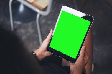 Kadın eli boş yeşil ekran siyah tablet PC'de modern loft kafede uylukta tutan mockup görüntü