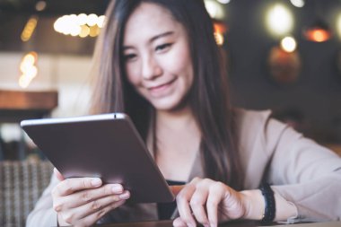 Portre resim bir güzel Asya iş kadın tutarak ve kafede tablet PC'yi kullanma