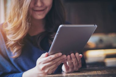 Gülücük yüzlü, güzel bir Asyalı kadın modern kafede tablet tablet kullanıyor.