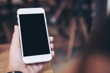 Modern restoranda boş siyah perde ile beyaz cep telefonu tutan el mockup görüntü