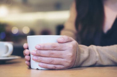 Modern kafede beyaz fincan kahve iki elle tutan bir kadın portre resmi