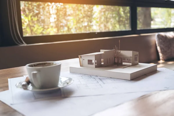 An architecture model with shop drawing paper and coffee cup on table in office