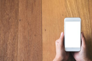 Kadının görüntüsünü mockup holding beyaz cep telefonu ile antika ahşap masa arka plan boş ekran eller