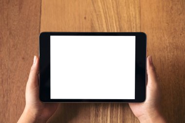 Mockup görüntü tutarak ve vintage ahşap masa üzerinde siyah tablet pc boş beyaz ekran ile gösterilen El 