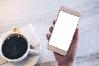 Boş beyaz ekran ve kafede mermer masada bir fincan kahve ile cep telefonu görüntüsünü mockup