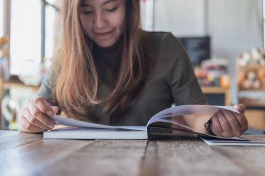 Portre resim güzel bir Asya kadının modern kafede bir kitap okuma 