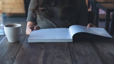 Bir kadın vintage Cafe ahşap masa beyaz kahve kupa ile bir kitap okuma portre resmi 