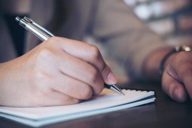 Ahşap masa arka plan üstünde boş defter üzerinde yazılı iş kadını closeup görüntü