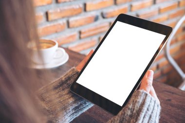 Kafede siyah tablet pc ile beyaz kahve Kupası tahta masada boş beyaz ekran ile holding eller mockup görüntü