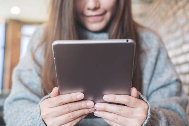Portre resim güzel bir Asya kadının tutarak ve modern kafede oturan tablet PC'yi kullanma