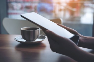 Portre resim tutarak ve kahve fincanı ahşap tablo ile tablet pc kullanarak bir kadının el Cafe arka plan bulanıklık