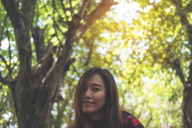 Güzel bir Asyalı kadın yeşil doğa arka planda mutlu duygu ile açık oturma portre portre görüntü