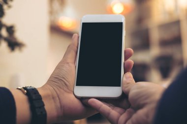 Mockup görüntü tutarak ve vintage kafede boş siyah perde ile beyaz cep telefonu kullanarak kadının el