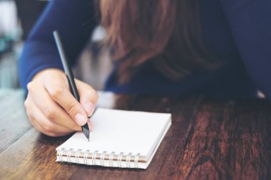 Kadın eli defter ile ahşap masa arka plan üzerinde yazma görüntüsünü kapatmak