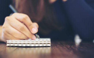 Kadın eli defter ile ahşap masa arka plan üzerinde yazma görüntüsünü kapatmak