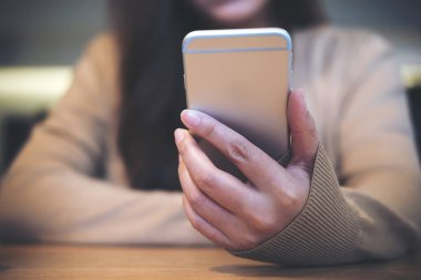 Tutan bir kadın, akıllı kullanarak ve bakarak vintage Cafe ahşap masa telefonu